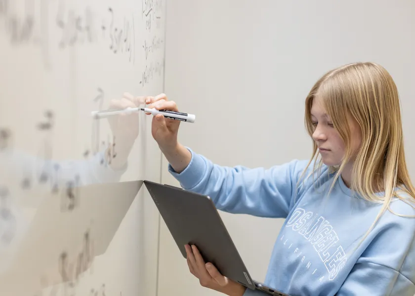 student working on a math equation on a whiteboard