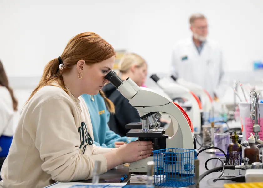 student looking at samples under a microscope
