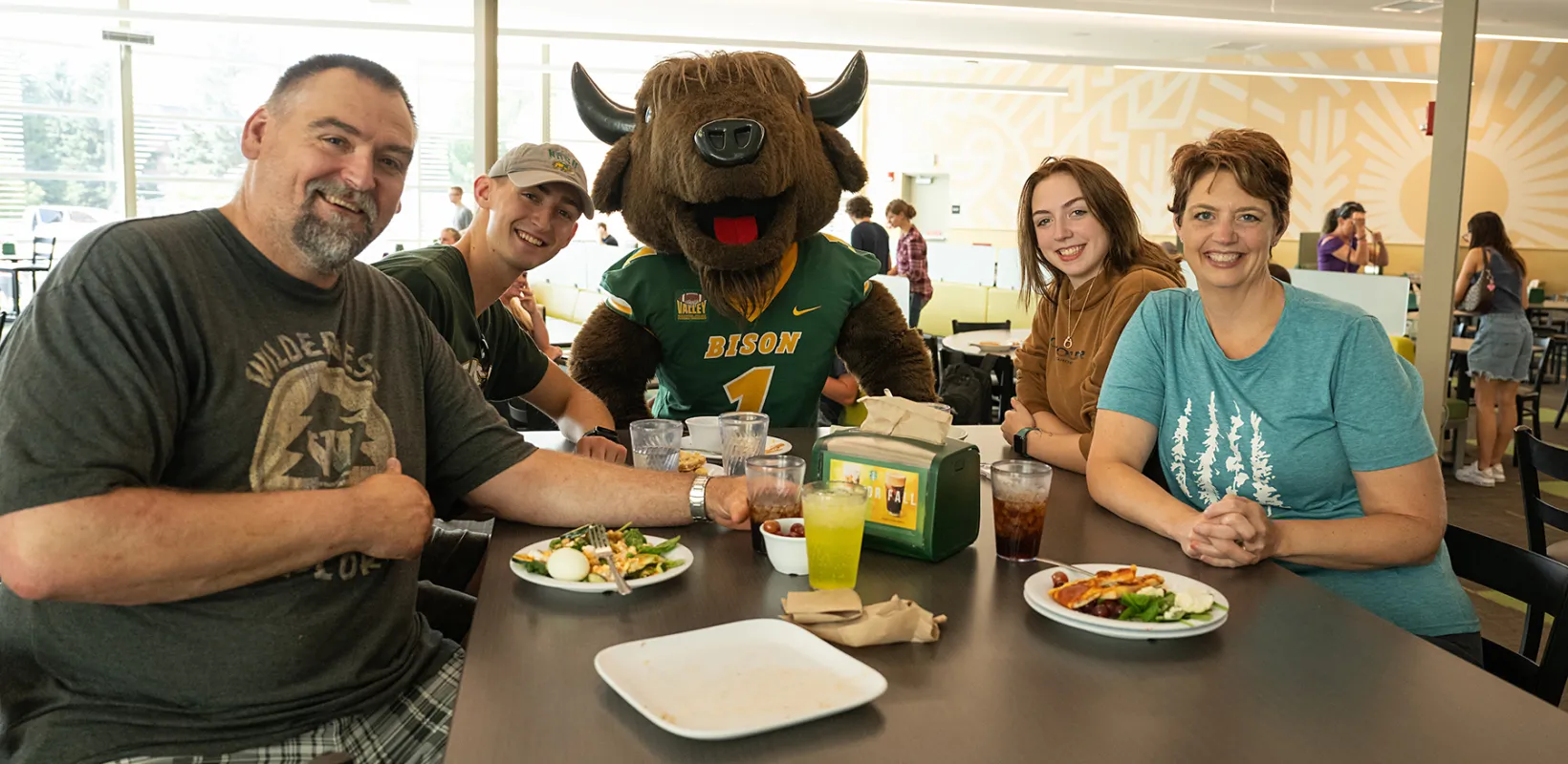 a new student with their family sitting with NDSU mascot, Thundar, at the Dining Center